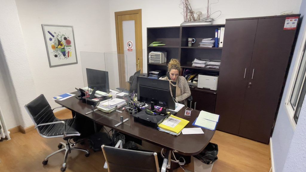 Asesora al teléfono con carpetas y documentos sobre su mesa en la gestoría