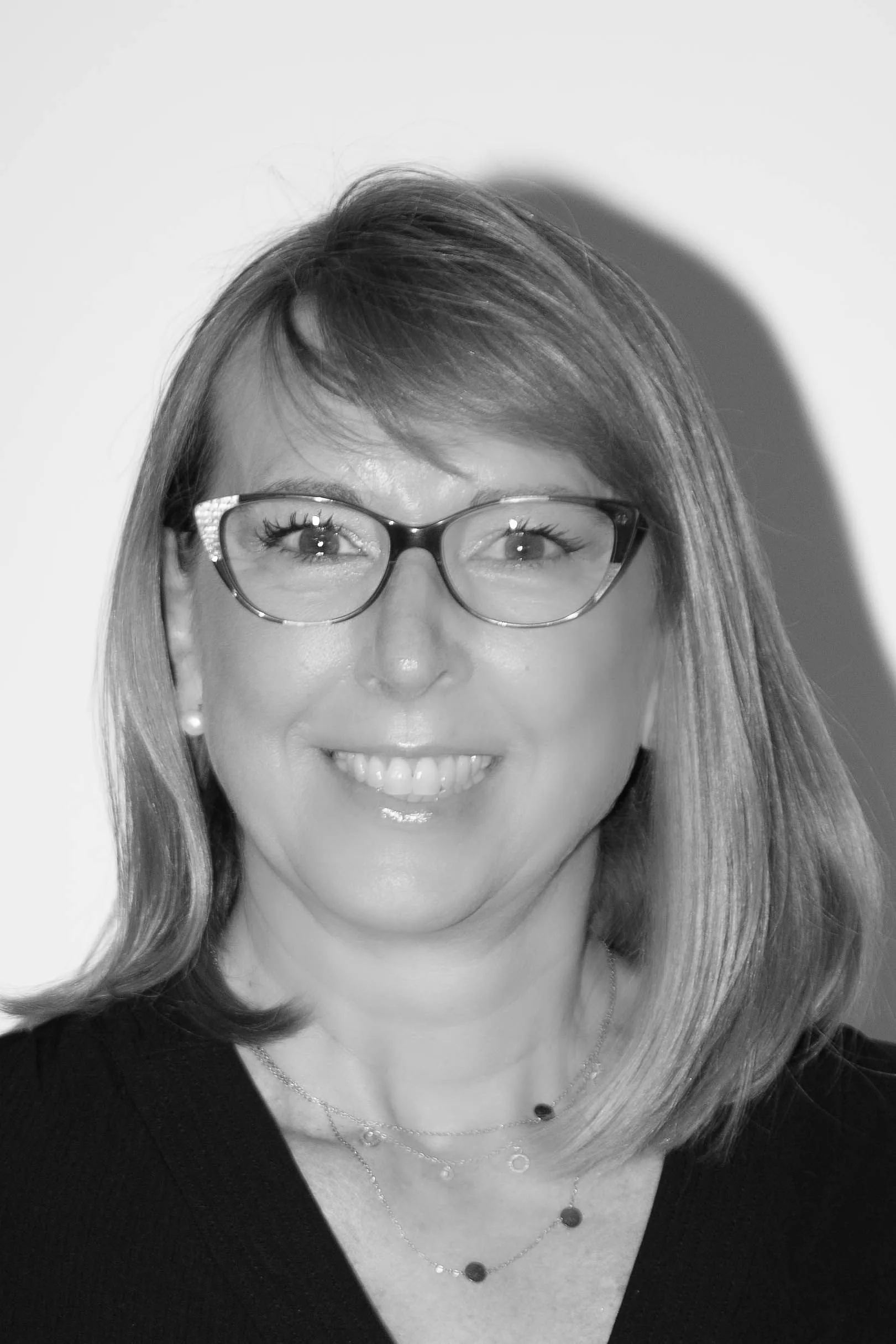 Asesoría consultoría Zaragoza Retrato en blanco y negro de una mujer rubia con gafas y collares finos, del equipo de asesoría y consultoría en Zaragoza