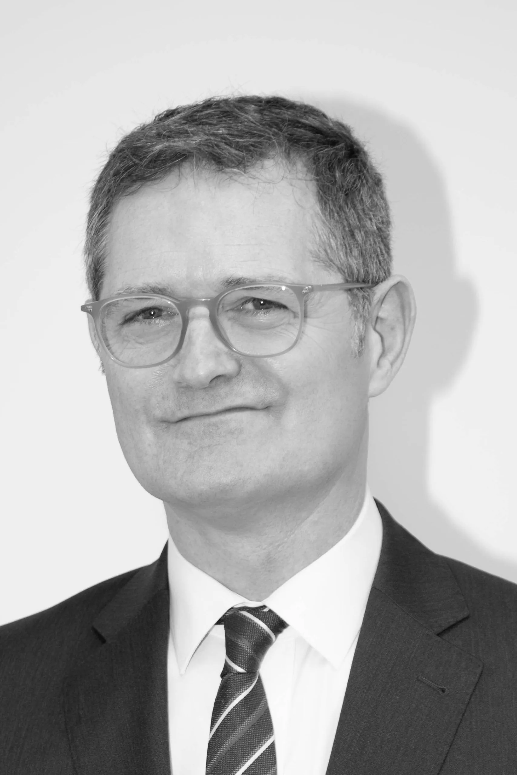 Gestor online Zaragoza Retrato en blanco y negro de un hombre con gafas, traje oscuro y corbata de rayas, gestor online en Zaragoza