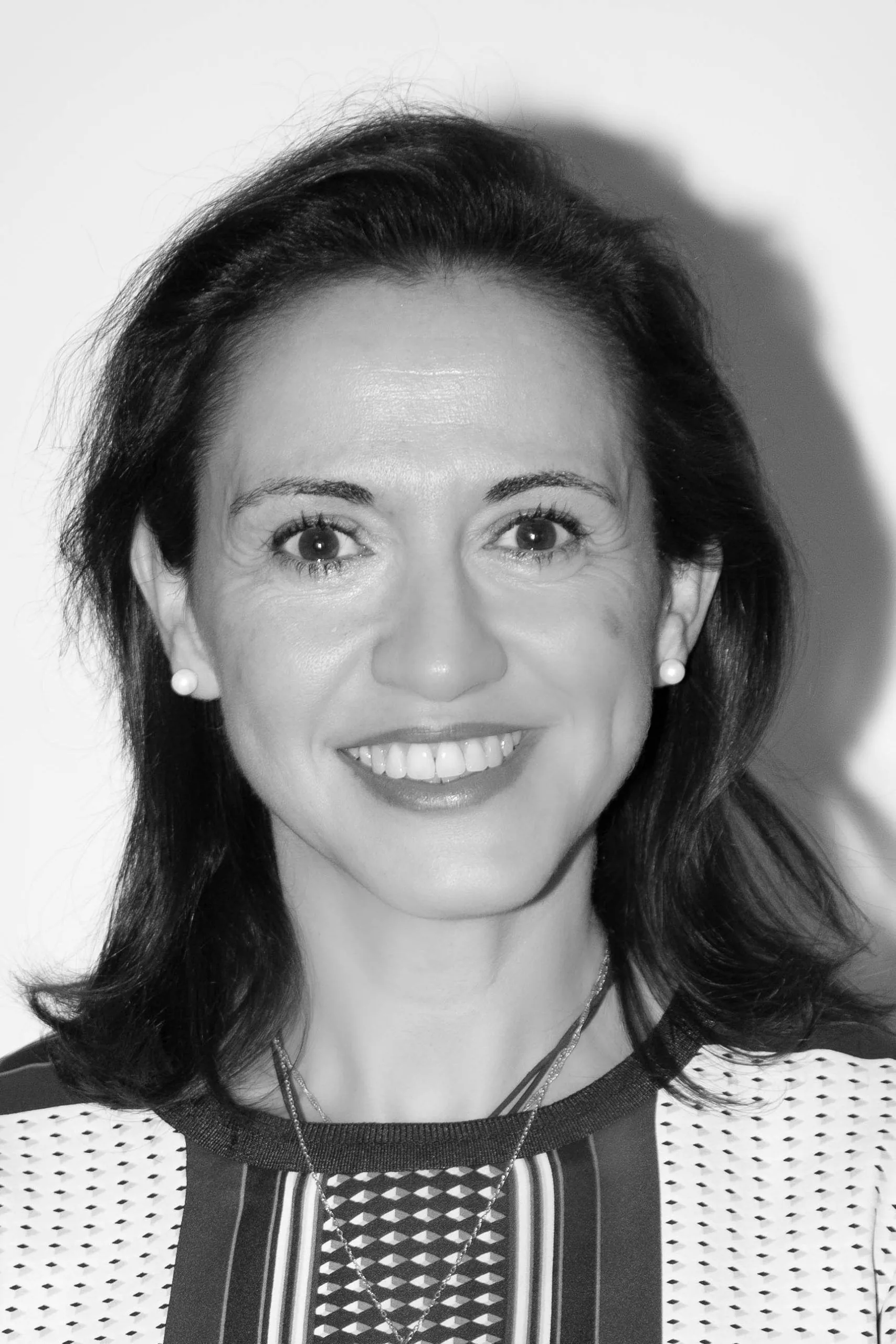 Gestoría profesional Zaragoza Retrato en blanco y negro de una mujer sonriente con pendientes de perla, de nuestra gestoría profesional en Zaragoza