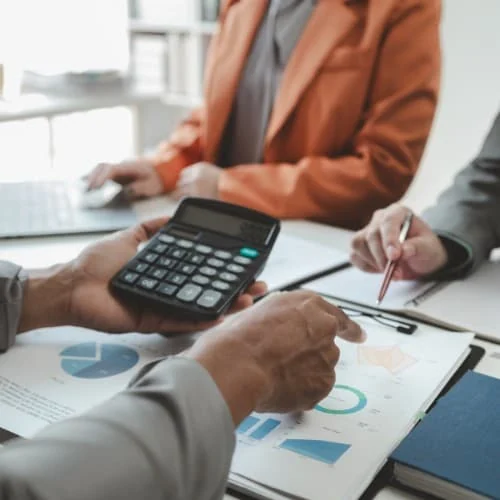 Dos personas repasan cuentas con una calculadora sobre documentos con gráficos en una de las gestorías en Zaragoza capital